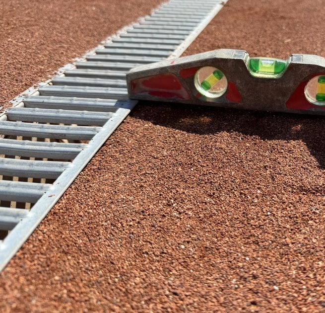 Wasserwaage auf einem Sandplatz neben der Entwässerungsrinne